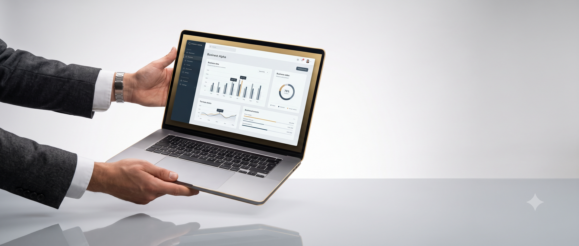 A person in a dark suit holds a silver laptop displaying a dashboard interface, set against a clean light gray studio background.